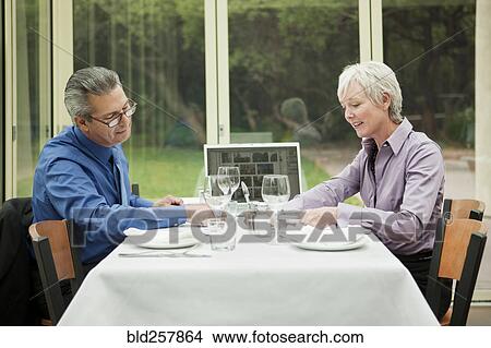 Picture - Business people with laptop working at table in restaurant. Fotosearch