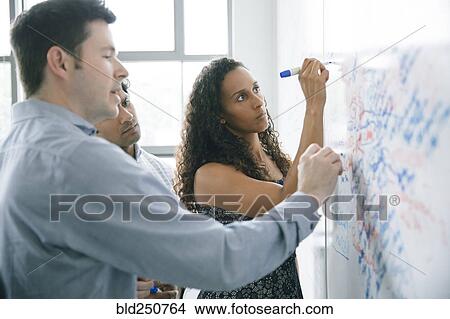 Picture - Business people writing on whiteboard in meeting. Fotosearch