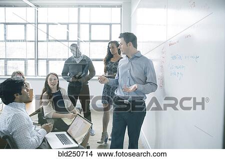 Picture - Businessman talking near whiteboard in meeting. Fotosearch