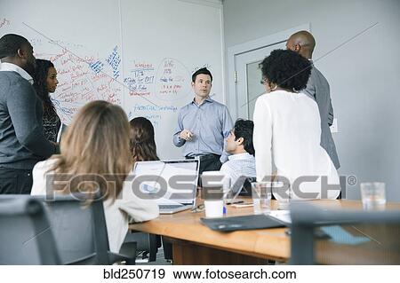 Businessman talking near whiteboard in meeting View Large Photo Image Stock Photo - Businessman talking near whiteboard in meeting. Fotosearch