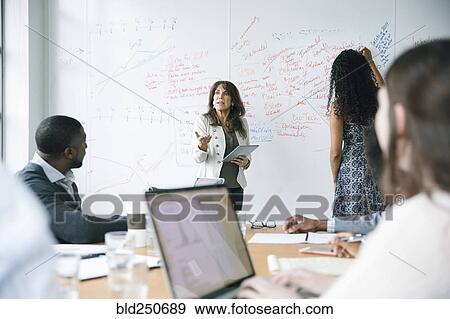 Businesswoman holding digital tablet near whiteboard in meeting View Large Photo Image Stock Photo - Businesswoman holding digital tablet near whiteboard in meeting. Fotosearch