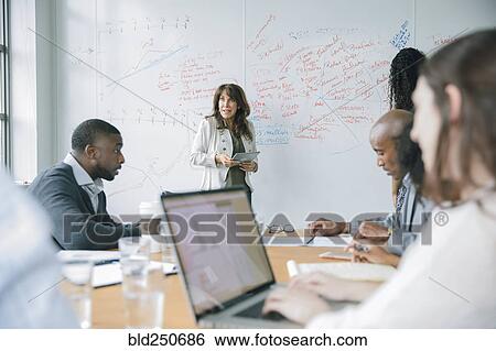 Businesswoman holding digital tablet near whiteboard in meeting View Large Photo Image Stock Photograph - Businesswoman holding digital tablet near whiteboard in meeting. Fotosearch