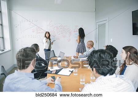 Picture - Businesswoman talking at whiteboard in meeting. Fotosearch
