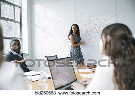 Stock Photo - Businesswoman talking at whiteboard in meeting. Fotosearch