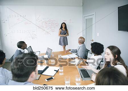 Stock Photography - Businesswoman talking at whiteboard in meeting. Fotosearch