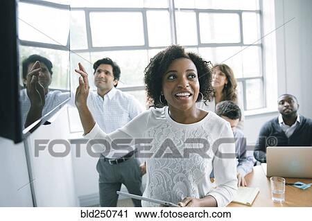 Businesswoman talking near visual screen in meeting View Large Photo Image Stock Image - Businesswoman talking near visual screen in meeting. Fotosearch