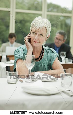 Stock Photo - Businesswoman talking on cell phone in restaurant. Fotosearch