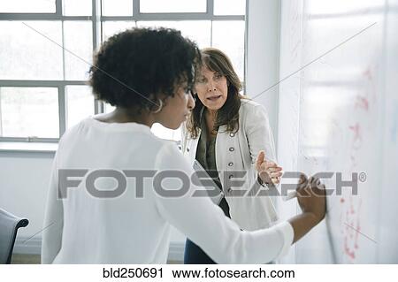 Businesswoman writing on whiteboard in meeting View Large Photo Image Stock Image - Businesswoman writing on whiteboard in meeting. Fotosearch