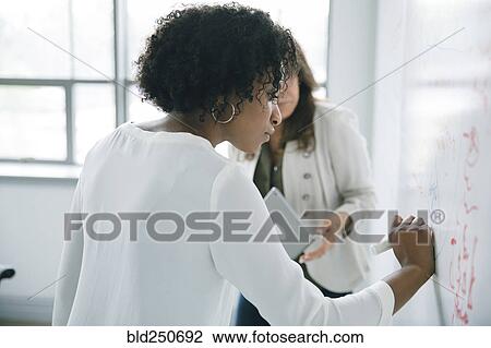 Businesswoman writing on whiteboard in meeting View Large Photo Image Stock Image - Businesswoman writing on whiteboard in meeting. Fotosearch