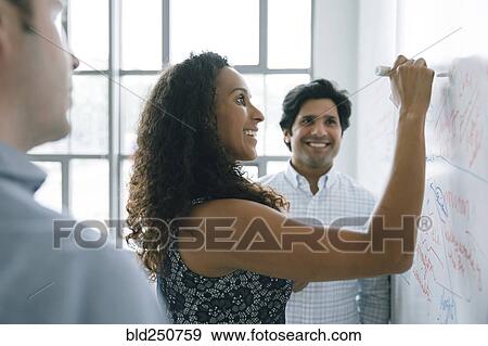 Stock Photo - Businesswoman writing on whiteboard in meeting. Fotosearch