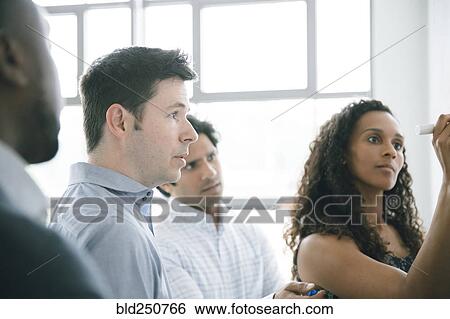 Stock Photograph - Businesswoman writing on whiteboard in meeting. Fotosearch