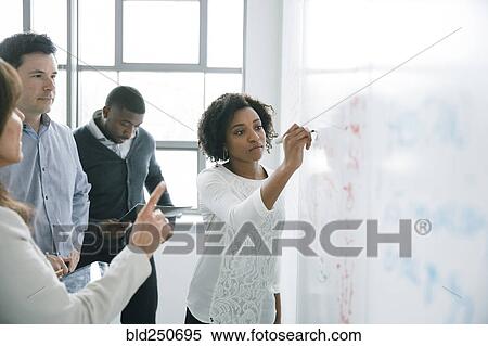 Stock Photography - Businesswoman writing on whiteboard in meeting. Fotosearch