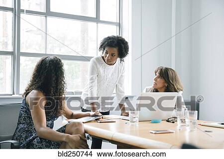 Picture - Businesswomen using laptop in meeting. Fotosearch