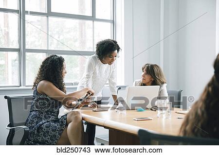 Stock Image - Businesswomen using laptop in meeting. Fotosearch