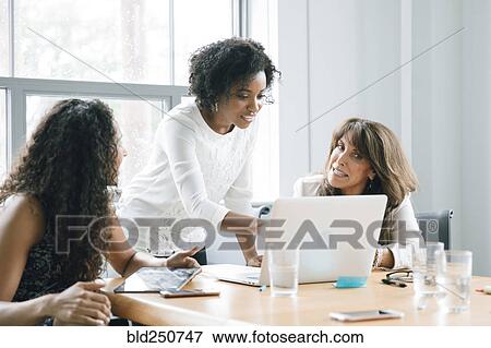 Stock Photo - Businesswomen using laptop in meeting. Fotosearch