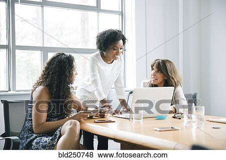 Stock Photo - Businesswomen using laptop in meeting. Fotosearch