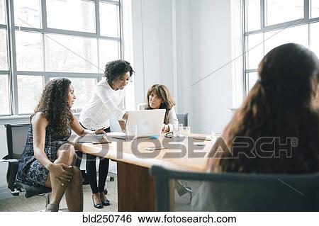 Businesswomen using laptop in meeting View Large Photo Image Stock Photograph - Businesswomen using laptop in meeting. Fotosearch