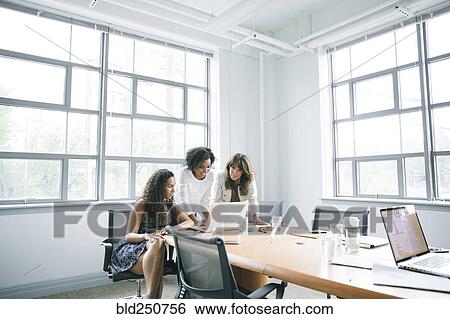 Stock Photograph - Businesswomen using laptop in meeting. Fotosearch