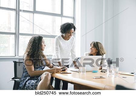 Stock Photography - Businesswomen using laptop in meeting. Fotosearch