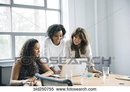 Businesswomen using laptop in meeting View Large Photo Image Stock Photography - Businesswomen using laptop in meeting. Fotosearch