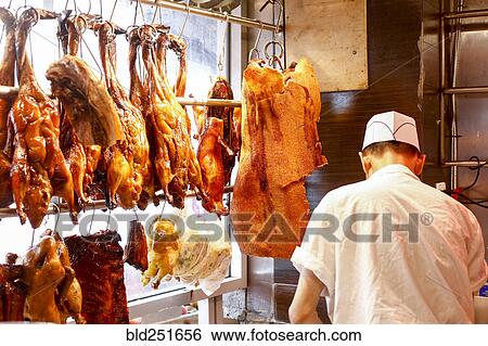 Stock Photograph - Butcher standing near hanging meat. Fotosearch