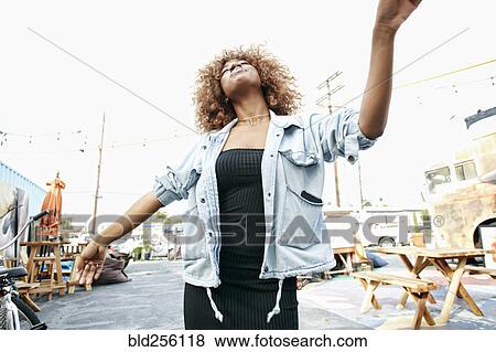 Stock Photo - Carefree Black woman dancing outdoors. Fotosearch