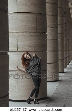 Stock Photo - Carefree Caucasian woman leaning on pillar. Fotosearch