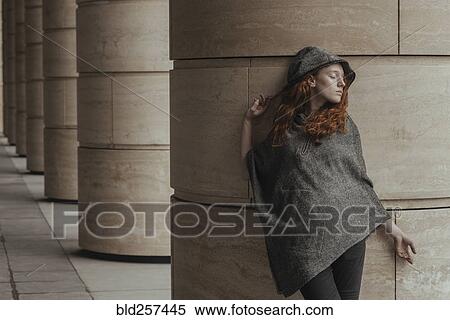 Stock Photography - Carefree Caucasian woman leaning on pillar. Fotosearch
