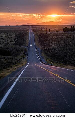 Picture - Cars driving on remote road at sunset. Fotosearch