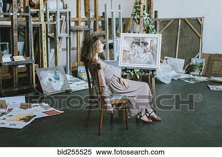 Stock Photography - Caucasian artist sitting near painting on easel. Fotosearch