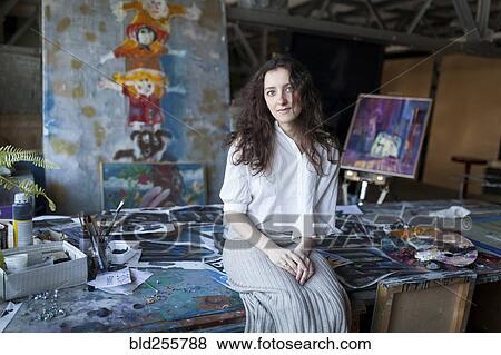 Caucasian artist sitting on table in studio View Large Photo Image Stock Photo - Caucasian artist sitting on table in studio. Fotosearch
