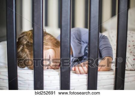 Stock Image - Caucasian baby girl sleeping in crib. Fotosearch