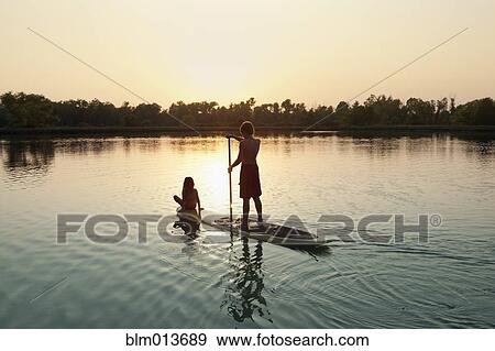 Stock Photo - Caucasian boy and girl on paddleboard on lake. Fotosearch