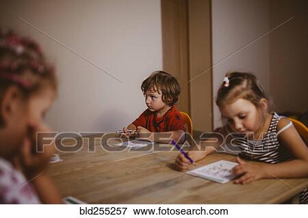 Stock Photo - Caucasian boy and girl sitting at table coloring. Fotosearch