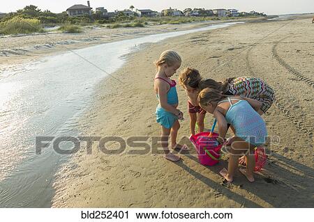 Caucasian boy and girls playing with pail on beach View Large Photo Image Stock Image - Caucasian boy and girls playing with pail on beach. Fotosearch