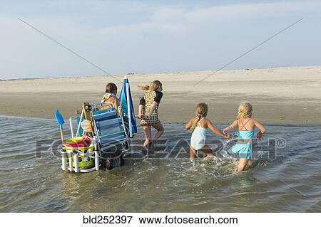 Stock Photo - Caucasian boy and girls pulling cart on beach. Fotosearch