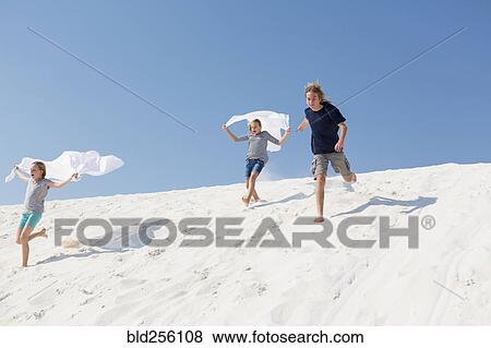 Caucasian boy and girls running on sand dune View Large Photo Image Stock Photo - Caucasian boy and girls running on sand dune. Fotosearch
