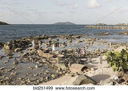 Stock Photo - Caucasian boy and girls walking on rocks at beach. Fotosearch