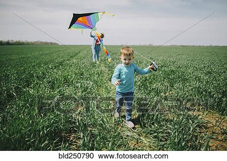Stock Image - Caucasian boy and grandmother flying kite in field. Fotosearch