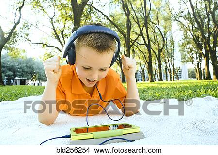 Caucasian boy celebrating on blanket in park with digital tablet View Large Photo Image Picture - Caucasian boy celebrating on blanket in park with digital tablet. Fotosearch