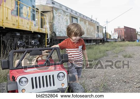 Picture - Caucasian boy holding toy car near train. Fotosearch