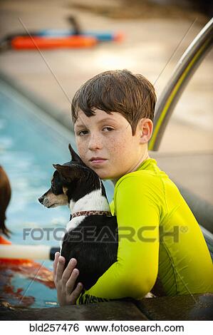 Stock Photograph - Caucasian boy in swimming pool holding dog. Fotosearch