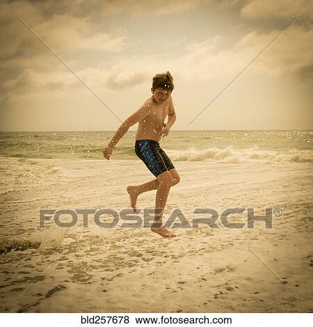 Caucasian boy jumping and splashing in ocean waves View Large Photo Image Stock Photo - Caucasian boy jumping and splashing in ocean waves. Fotosearch