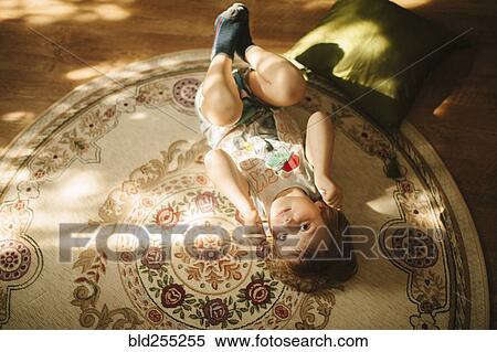 Stock Photography - Caucasian boy laying on rug. Fotosearch