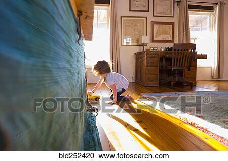 Stock Image - Caucasian boy on the floor playing with toy truck. Fotosearch