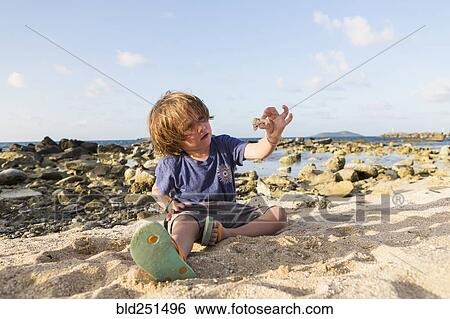 Stock Photograph - Caucasian boy playing in sand at beach. Fotosearch