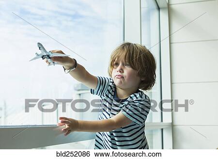 Caucasian boy playing with toy airplane near window View Large Photo Image Stock Photograph - Caucasian boy playing with toy airplane near window. Fotosearch