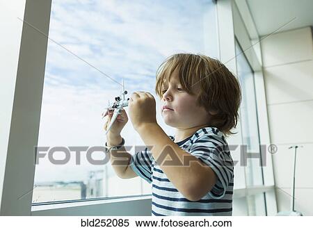 Caucasian boy playing with toy airplane near window View Large Photo Image Stock Photography - Caucasian boy playing with toy airplane near window. Fotosearch