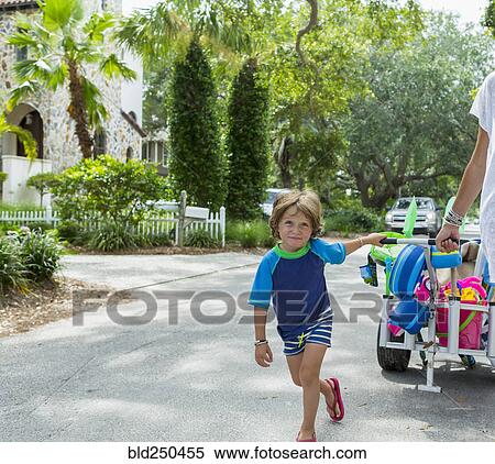 Caucasian boy pulling cart in street with mother View Large Photo Image Stock Photography - Caucasian boy pulling cart in street with mother. Fotosearch