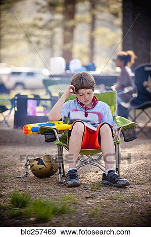 Stock Photo - Caucasian boy reading book at campground. Fotosearch
